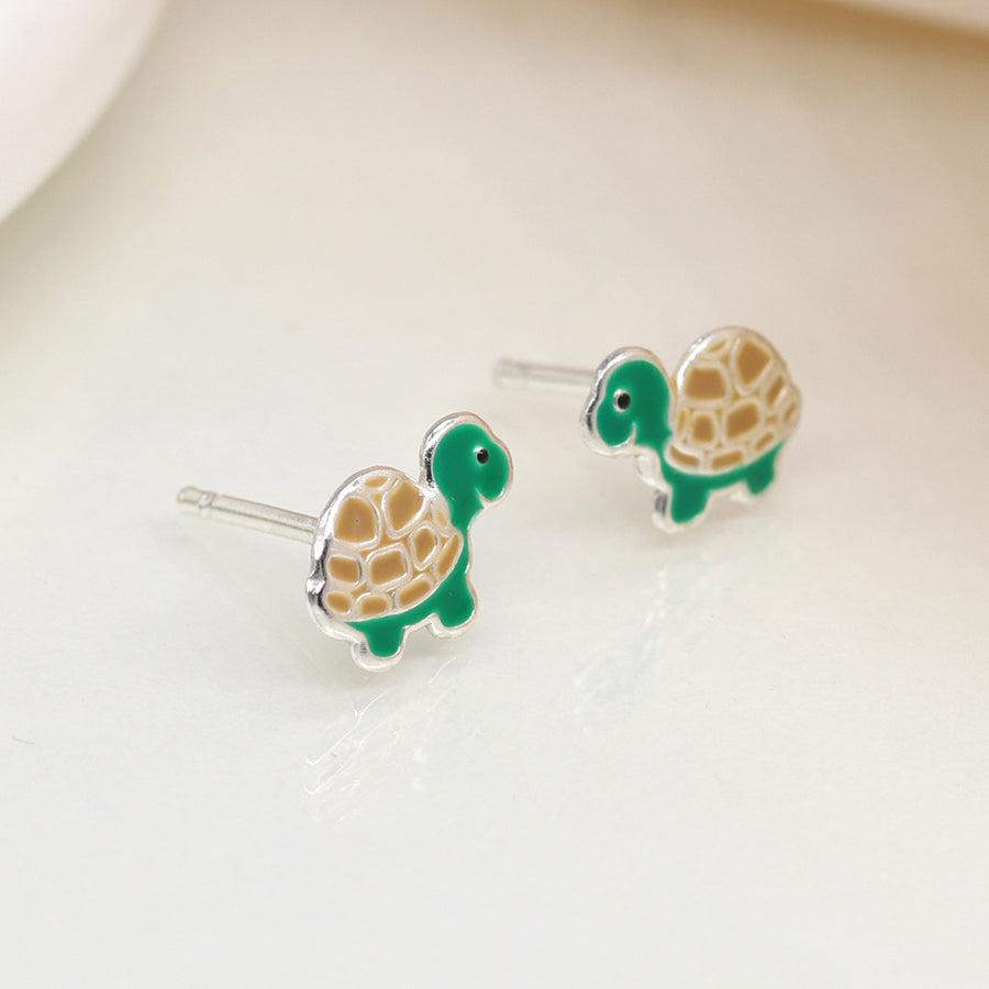 Sterling silver turtle stud earrings with green enamel shell and cream detailing, shown side-by-side on a neutral background.