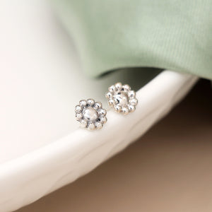 Close-up of sterling silver flower earrings showing beaded petal detail.