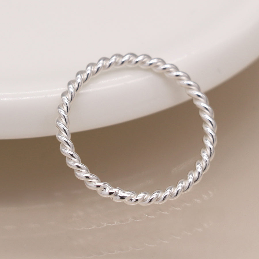 Top-down view of sterling silver twisted band ring on ceramic plate.