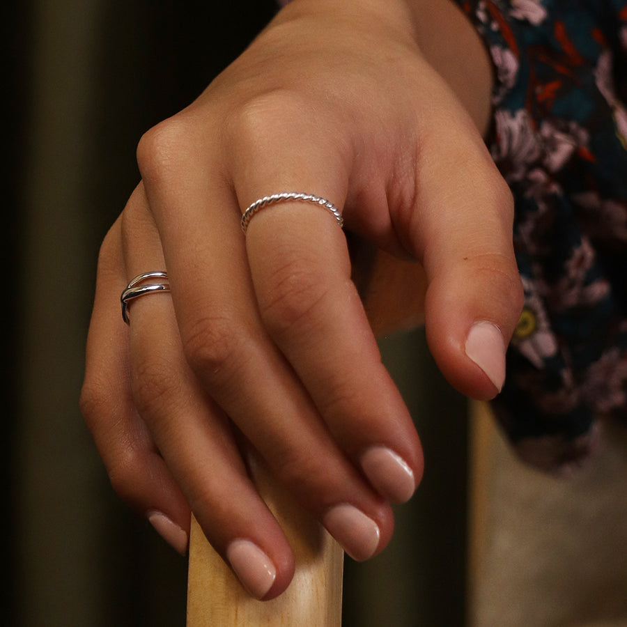 Model wearing sterling silver twist ring on finger with nude nails.