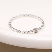 Sterling silver twist ring with square CZ crystal on white dish.