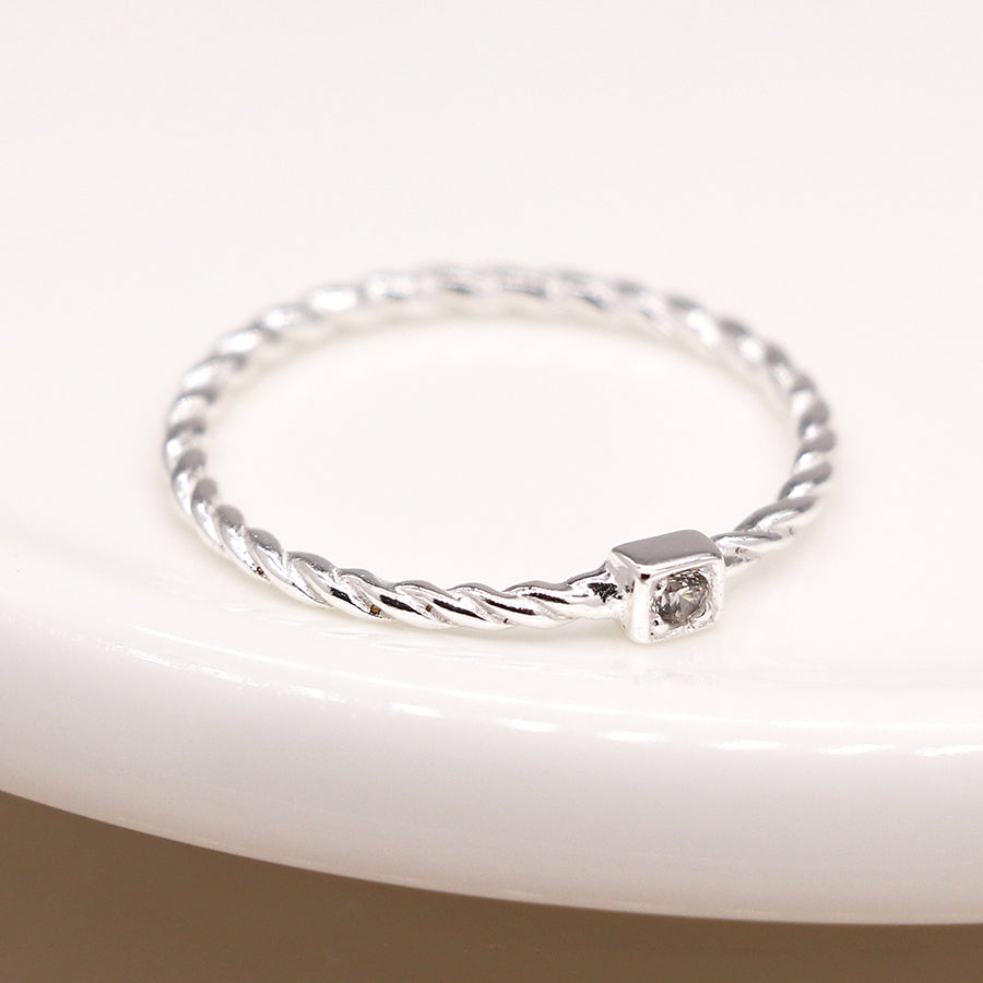 Sterling silver twist ring with square CZ crystal on white dish.