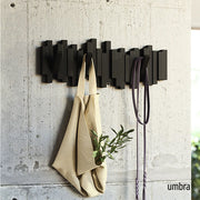 Umbra Sticks wall hook in black on concrete wall with bag and accessories