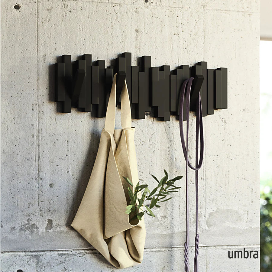 Umbra Sticks wall hook in black on concrete wall with bag and accessories