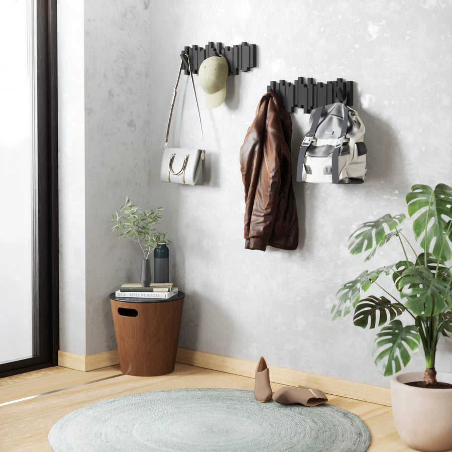 Sticks wall hook black on dark wall in entryway with coats and plant