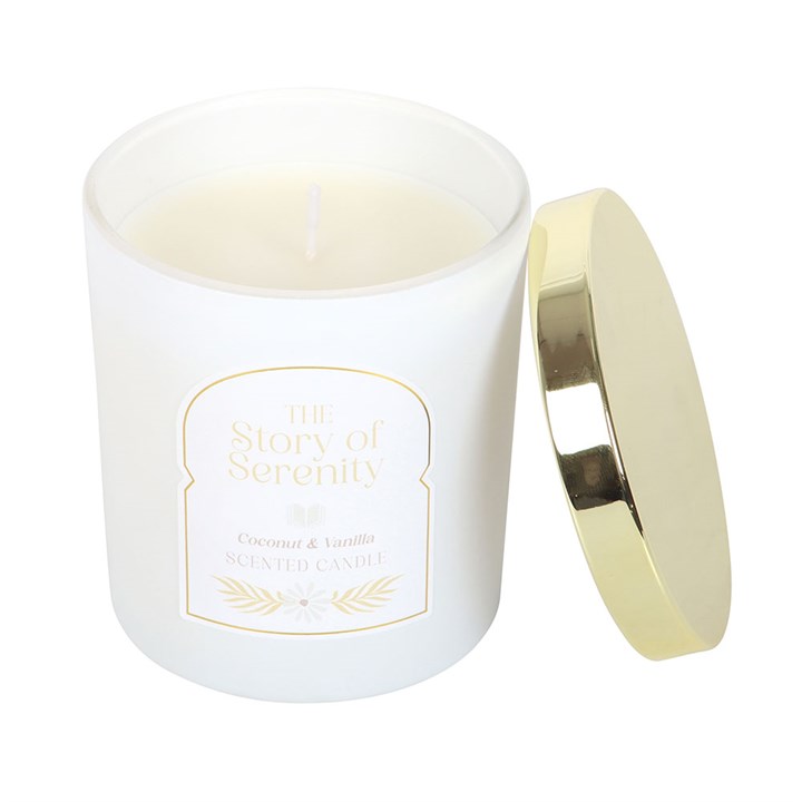 Open The Story of Serenity Coconut & Vanilla Candle in frosted white jar with gold lid resting on side.
