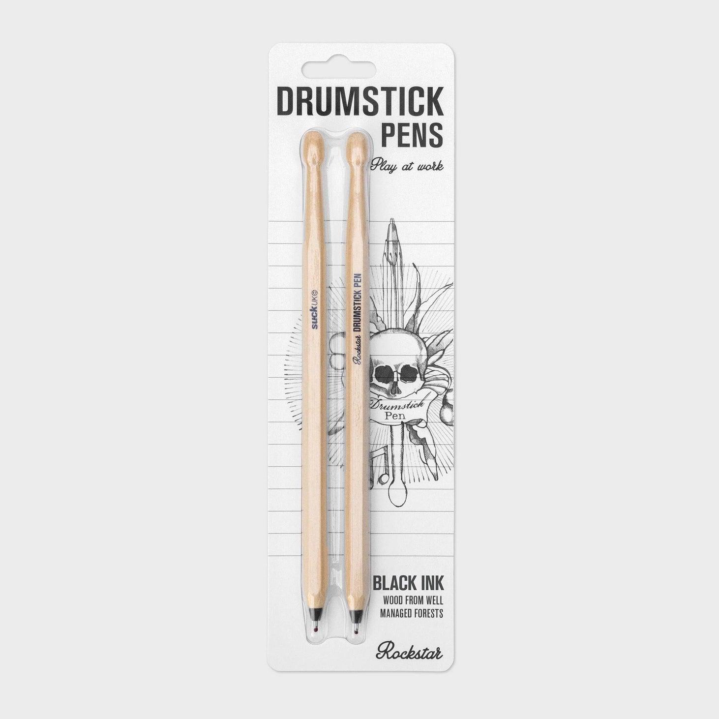 Retail packaging of Suck UK Drumstick Pens set with rock-themed backing card, featuring skull artwork and “Play at Work” slogan.