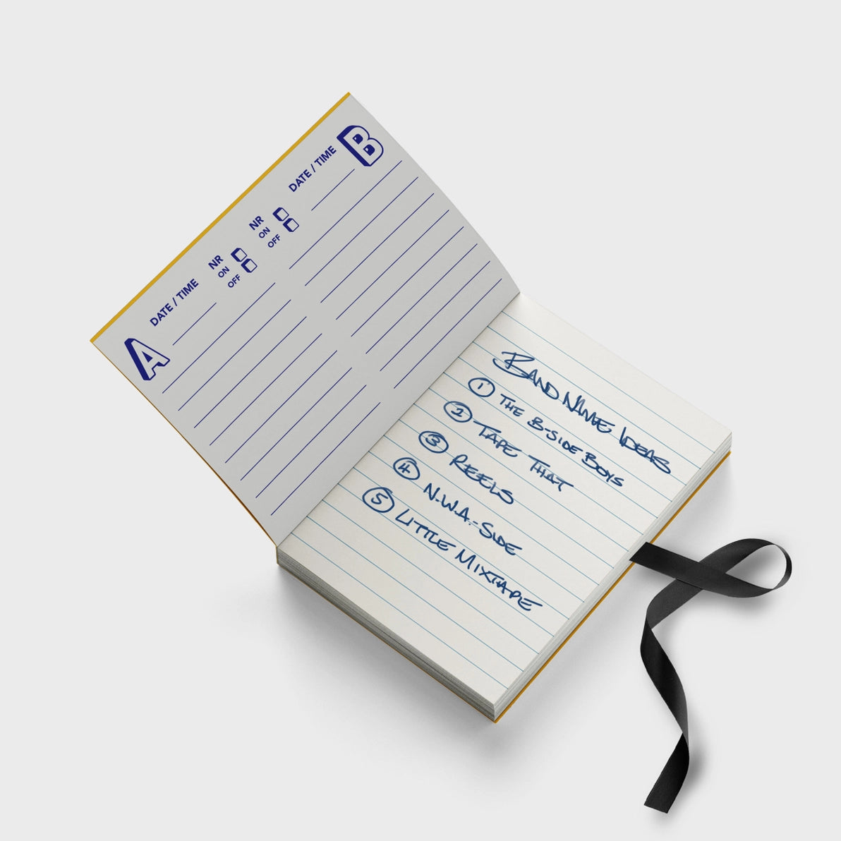 Open Mixtape Notebook showing lined pages and cassette-style inside cover, with a ribbon bookmark resembling unwound tape
