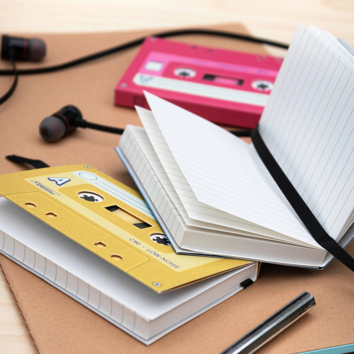 Mixtape Notebooks spread open on a desk, with visible lined pages and cassette-style covers in yellow and pink