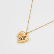 Gold-plated heart locket necklace featuring a hand-painted enamel design of two swallows and pink flowers on a fine chain.
