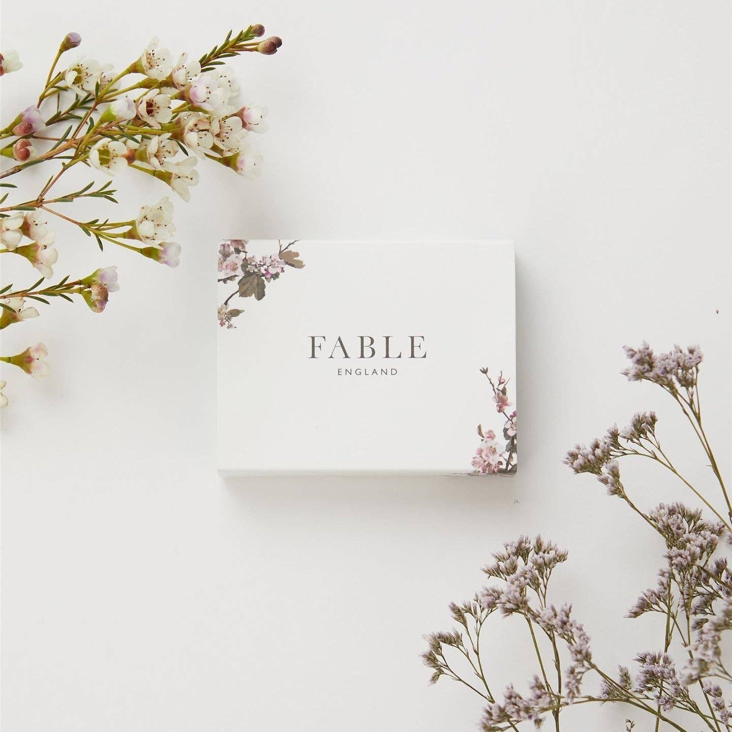 Fable England jewellery gift box with floral accents, styled with soft pastel flowers on a white background.