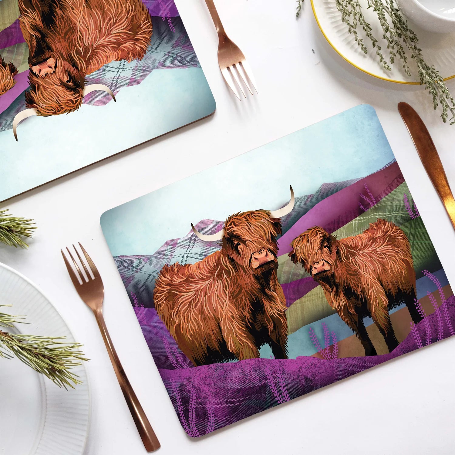 Tartan Highland Cow Placemats on a dining table with cutlery and a cup.