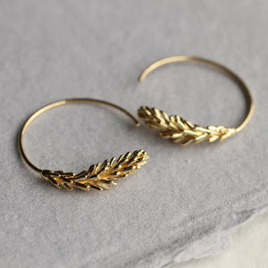 A model wearing Tiny Gold Leaf Hoop Earrings, featuring delicate botanical-inspired rosemary leaf details in gold.