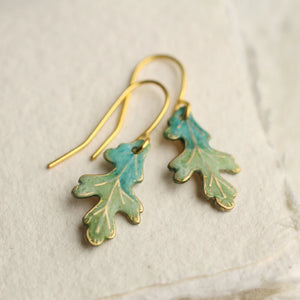 Close-up of Tiny Oak Leaf Earrings with turquoise patina on a gold-plated hook, displayed on a neutral background.