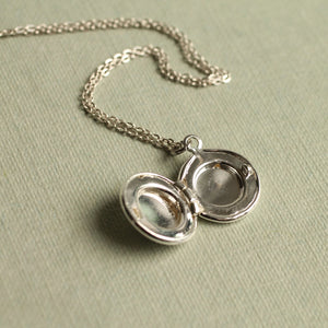 Open tiny round silver locket showing space for a miniature photo or keepsake – elegant personalised necklace on a chain.