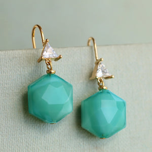 Angled close-up of faceted turquoise earrings with crystal triangle and gold hooks, bold art deco drop earrings.