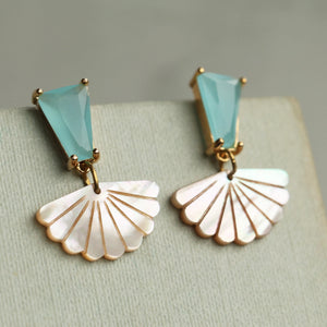 Front-facing close-up of turquoise opal and mother of pearl art deco earrings on fabric display, featuring gold-plated brass setting and scallop fan shape.