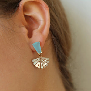 Close-up of turquoise opal and mother of pearl fan earring worn on ear, highlighting gold-plated setting and subtle shimmer of the carved shell design.