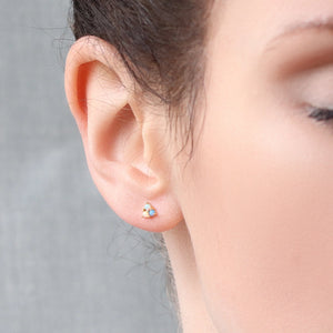 Model wearing a tiny triangular opal stud earring, showing its elegant size and vibrant colour contrast against the skin.