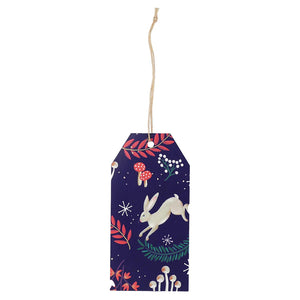 Detailed image of one recyclable woodland-themed gift tag with white hare, mushrooms, and foliage on a deep blue background.