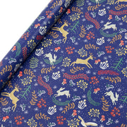 Festive recycled Christmas wrapping paper with woodland animals and jewel-tone florals on navy blue background, shown partially unrolled.