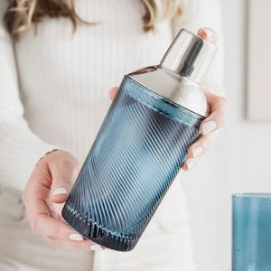Person holding a blue twisted glass cocktail shaker with stainless steel top – stylish home bar essential