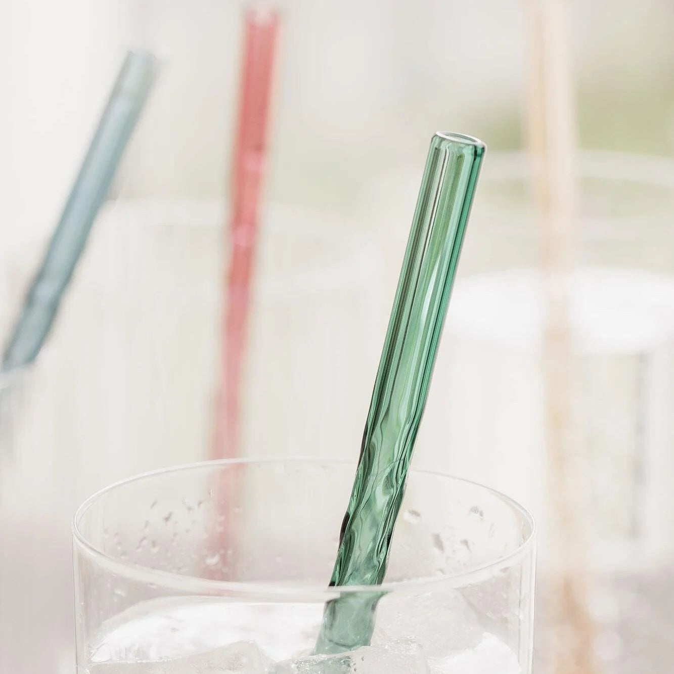 Green twist straw close-up in glass of ice water.