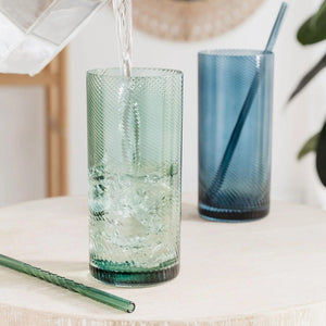 Pouring water with ice cubes into the green highball tumbler, with the blue glass in the background.