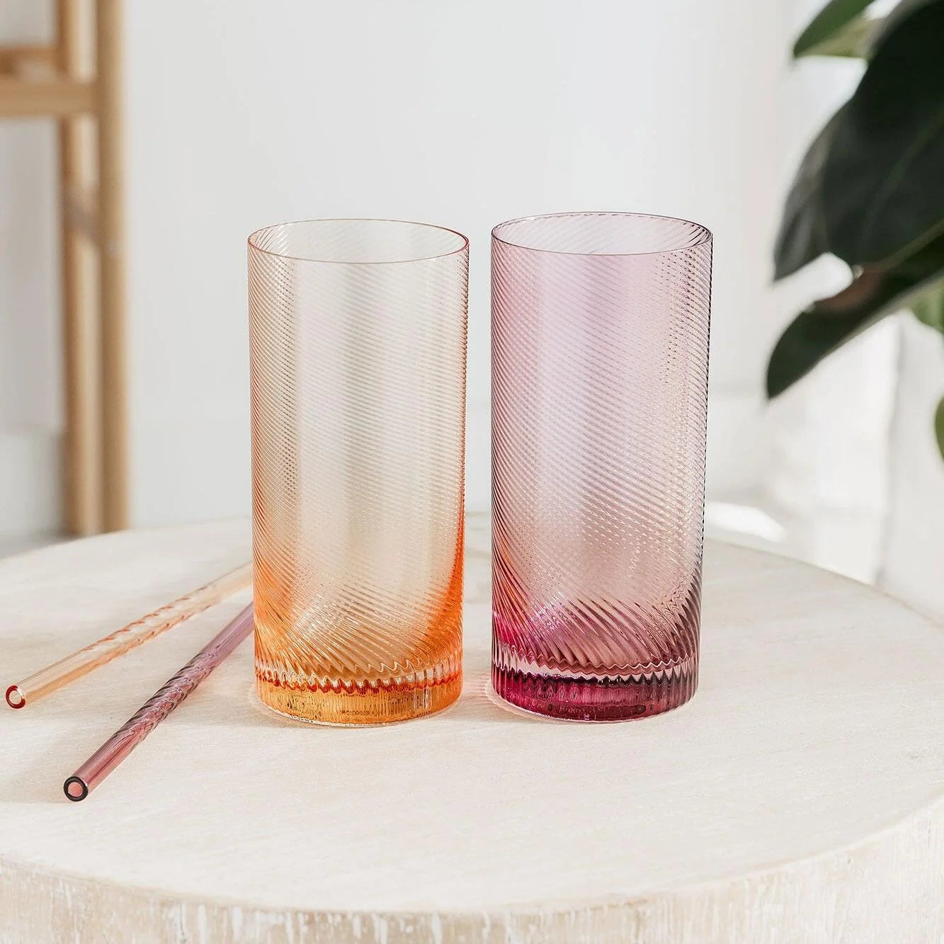 Set of 2 pastel twist glass tumblers in pink and peach on wooden table.