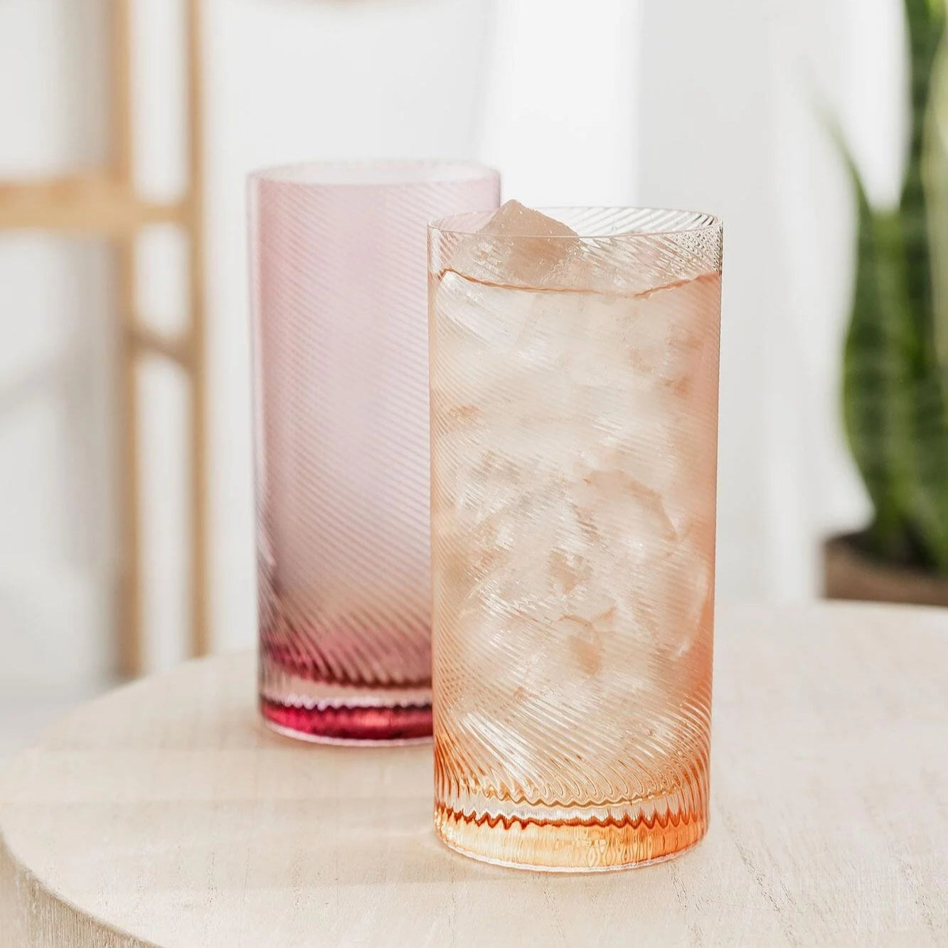 Pink and peach highball tumblers styled on table with ice drink.