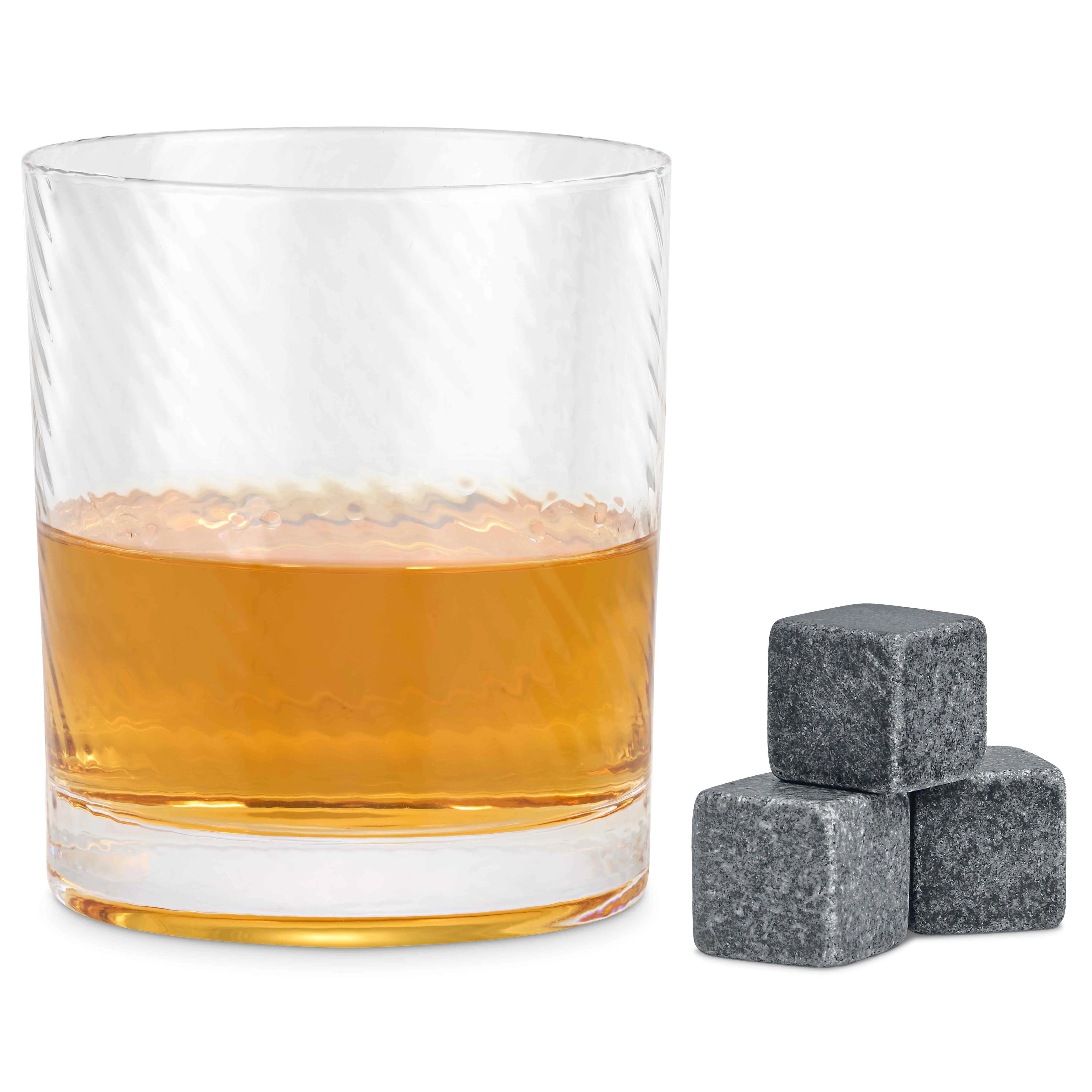 Whisky-filled twist spinning glass with granite whisky stones beside it on white background.