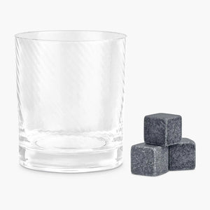 Clear twist-pattern whisky glass with three granite whisky stones on white background.
