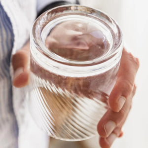 Hand holding handmade twist whisky glass with rounded spinning base.