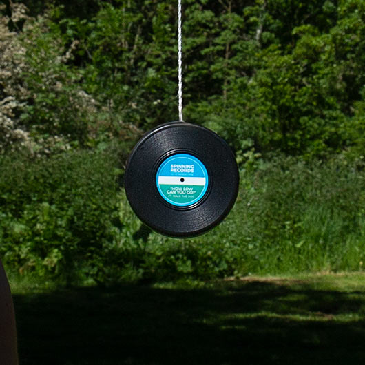 Retro vinyl yoyo spinning outdoors with string extended.