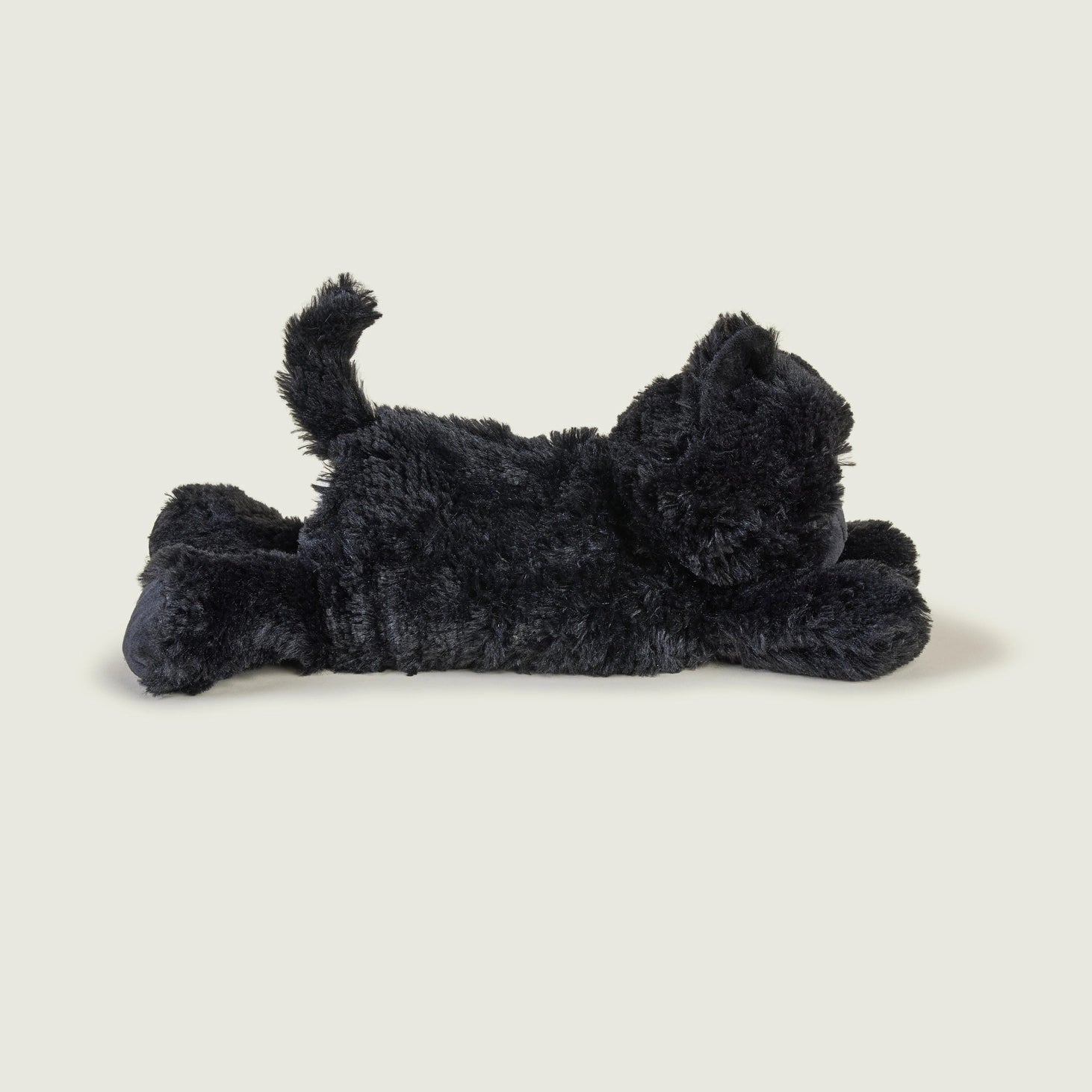 Side view of Warmies Black Cat microwavable cuddly toy lying flat, showing its plush tail and smooth black fur.