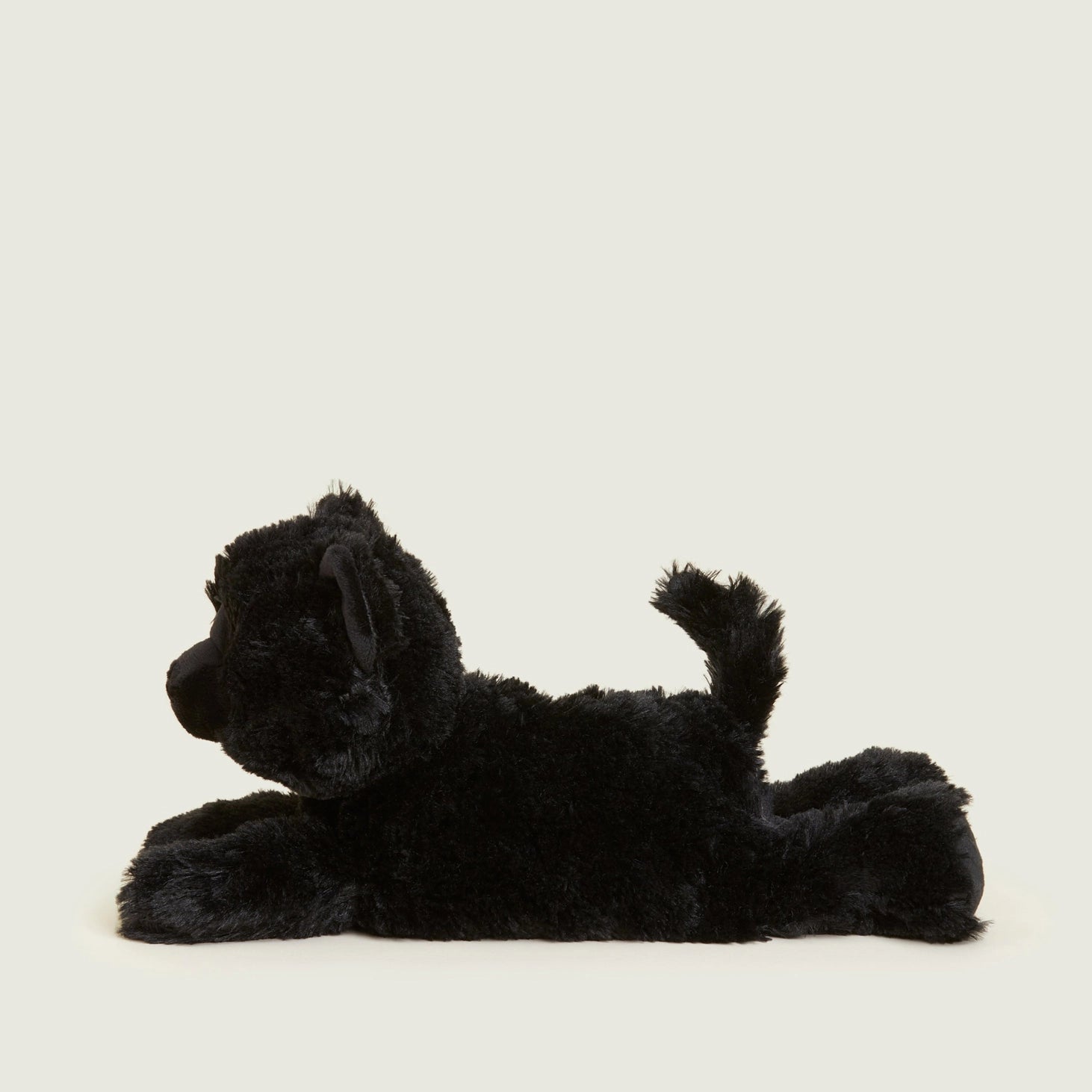 armies Black Cat heatable plush toy shown from the side on a cream background, highlighting its soft and cosy design.