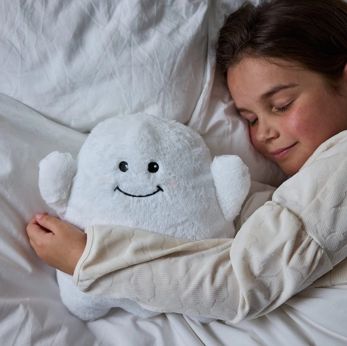 Child sleeping with Warmies Ghost heatable soft toy in bed, showing cuddly design.