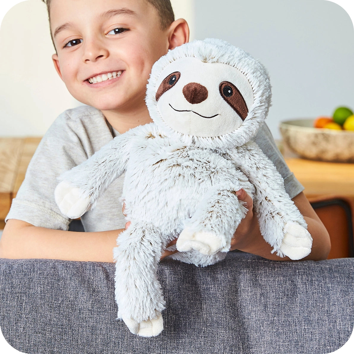 Child holding Warmies Marshmallow Sloth cuddly toy demonstrating size and huggable design.