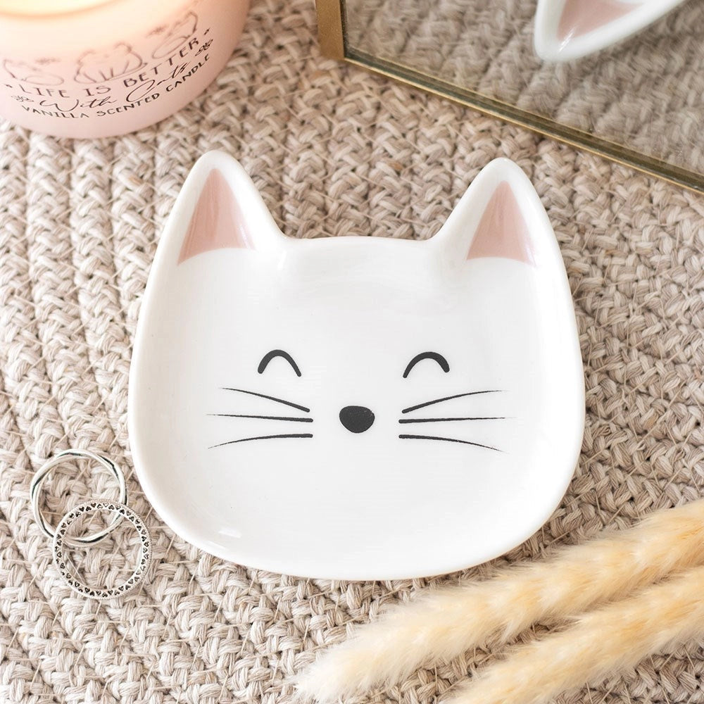 White cat face trinket dish with pink ears and whiskers on woven surface.