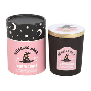Witching Hour candle and gift box side-by-side, showing black glass jar with illustrated witch face lid and pink starry-themed packaging.