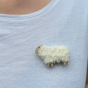 Close-up of Woolly Ewe brooch worn on a light blue shirt, showing detailed wool texture and miniature sheep shape, handmade in Scotland.