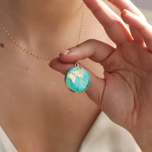 Globe locket necklace with hand-enamelled turquoise oceans and gold continents, shown worn on an 18-inch chain for a travel-inspired jewellery look.