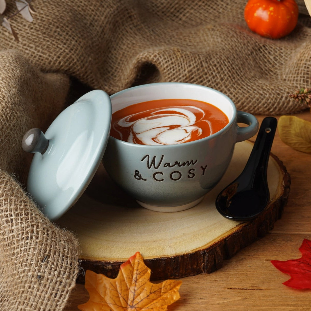 Warm and cosy soup bowl with tomato soup and swirl cream, styled in an autumn scene with leaves and pumpkins