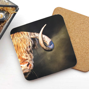 A Curly Gaze Highland Cow coaster with a detailed illustration of a Highland cow’s face, featuring a large curved horn, placed on a white surface with a cork backing visible.