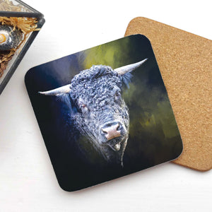 A Fuzzy Blue Highland Cow coaster featuring a striking blue-hued cow portrait, placed on a white surface with a cork backing visible.