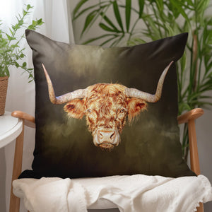 Rusty Rebel Highland Cow Cushion on an armchair – A cosy Highland cow cushion with a rich, earthy background, styled in a bright, plant-filled interior.