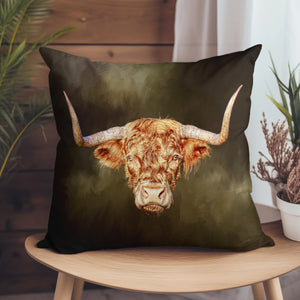 Rusty Rebel Highland Cow Cushion on a wooden chair – A square suede cushion featuring a bold Highland cow print with large horns, placed on a wooden chair for a rustic home setting.