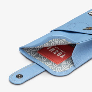 Inside of blue leather glasses case with press stud tab open, revealing patterned lining and red Yoshi label.