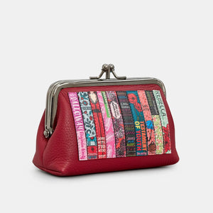 Angled view of cherry red leather purse showing kiss-lock frame and colourful embroidered book spines.