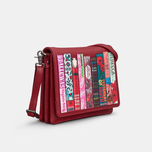 Angled side view of cherry red book-themed handbag with flap-over design.